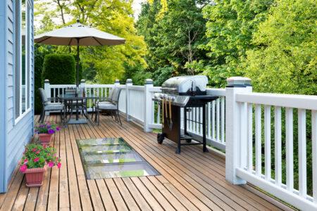 outdoor spaces with walkable glass skylights in a wooden deck with patio furniture and a grill
