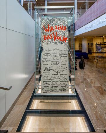 a piece of the Berlin Wall protected with glass with a walkable glass floor 