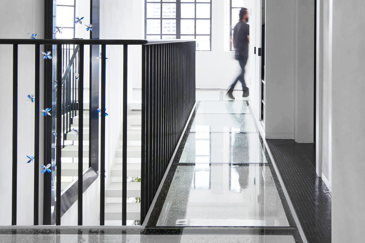 A man walking across multiple glass skylights embedded in the second-story floor