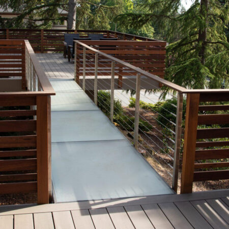 A glass bridge connecting a deck walkway with a wooden patio