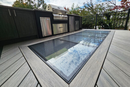 A deck with a grill embedded in the deck with a glass skylight in the floor