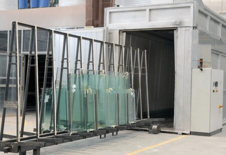 Industrial setting with multiple glass panels ready to enter a heat soak test chamber.