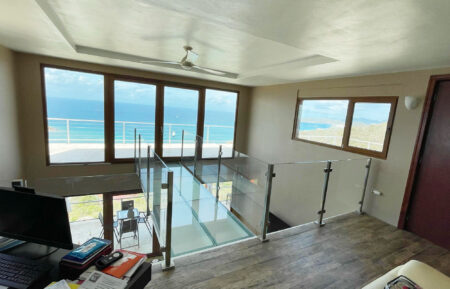 A luxurious beach house interior featuring a glass floor catwalk with stunning sea views.