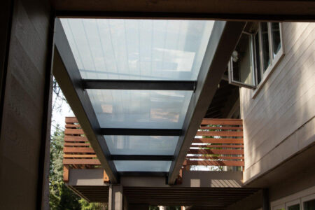 A modern glass-covered walkway between home structures, enhancing natural light.