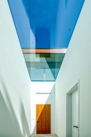 Minimalist corridor with a skylight showcasing bright blue skies above.