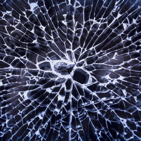 Close-up of a shattered glass texture displaying intricate crack patterns.