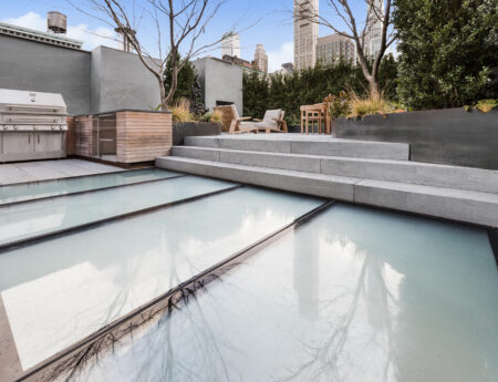 Luxurious rooftop patio with spacious glass panels as flooring, offering a sleek and stylish outdoor area with surrounding greenery and city views.