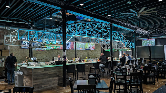 A bar area with a replica of the Corpus Christi Harbor Bridge lit up in blue above it, reflecting a piece of local architectural history.