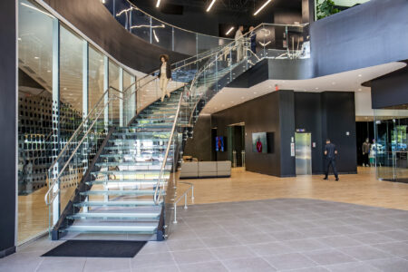 A wide view of the glass stairs at Mercedes-Benz, showcasing their modern design, clear glass treads, and surrounding minimalist decor.