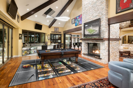 Modern living room with a pool table set atop a transparent glass floor, highlighting a display of collectibles beneath, creating a visually striking feature.