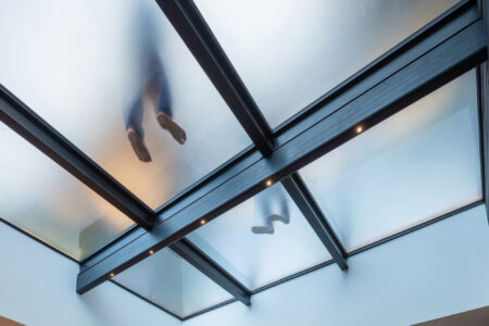 View of a walkable frosted glass ceiling with feet visible from below, highlighting the sleek and durable design of anti-slip glass surfaces.