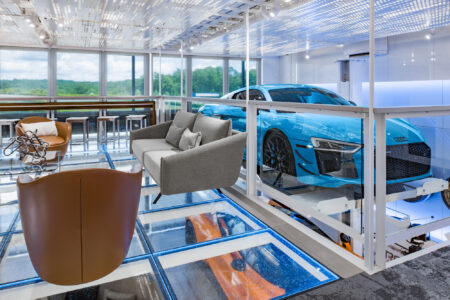 A luxury showroom with a glass floor displaying high-end vehicles, combining functionality with striking modern aesthetics.