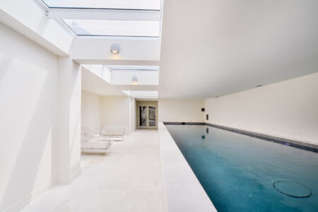 Indoor pool area with overhead skylights providing natural light, creating an elegant and bright atmosphere.