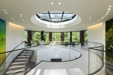 Circular walkable skylight in a contemporary home, illuminating a stylish staircase and living area with natural light.