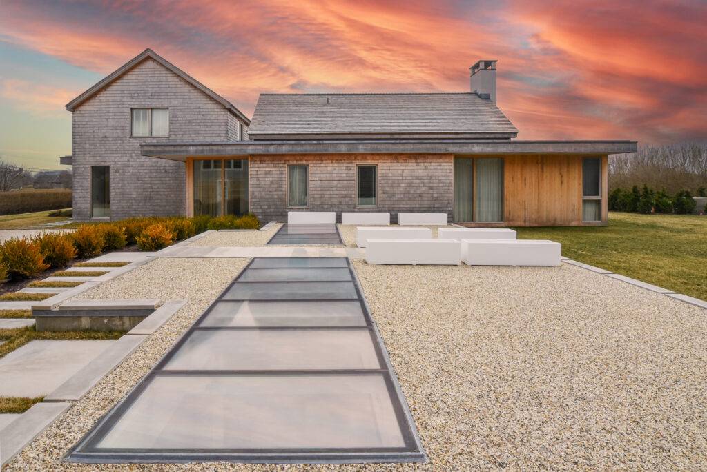 A modern home with sleek walkable skylights embedded in an outdoor patio, creating a seamless indoor-outdoor connection.