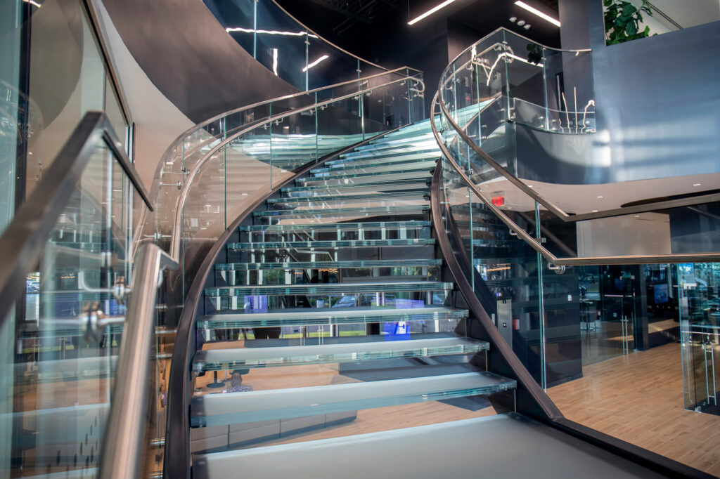 Striking spiral glass staircase with transparent steps and glass railings, creating a sophisticated focal point in a modern interior.