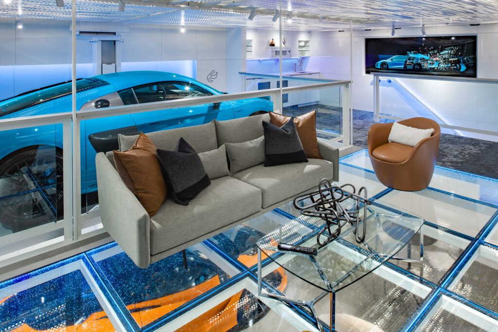 Stylish lounge with a glass floor reveals a blue sports car beneath, showcasing architectural glass innovation.