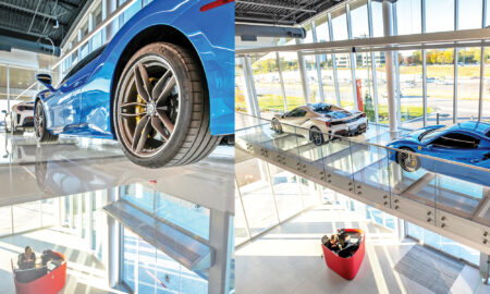 Sports cars displayed on a suspended glass floor above a lobby area with full-height glass walls.