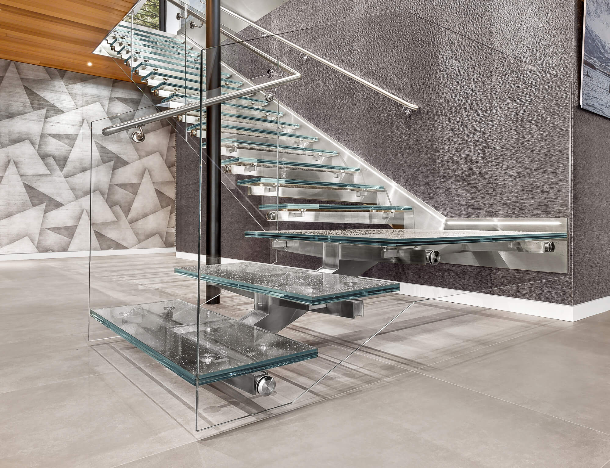 A glass staircase with a metal frame and handlebars.