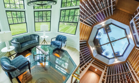 A luxurious sitting room with blue velvet chairs and a round glass coffee table features a large octagonal glass floor that reveals a wine cellar below.