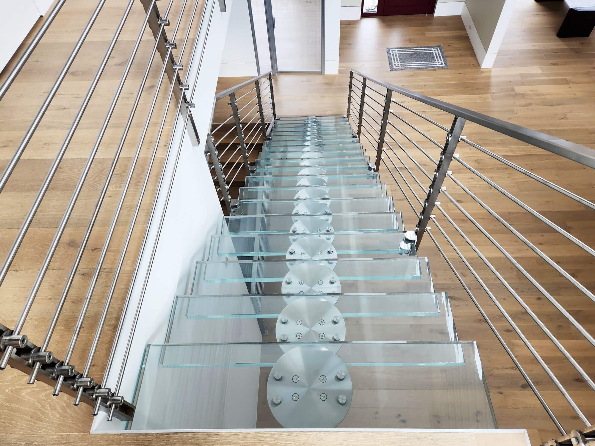Glass stairs with steel rails and a wood floor.