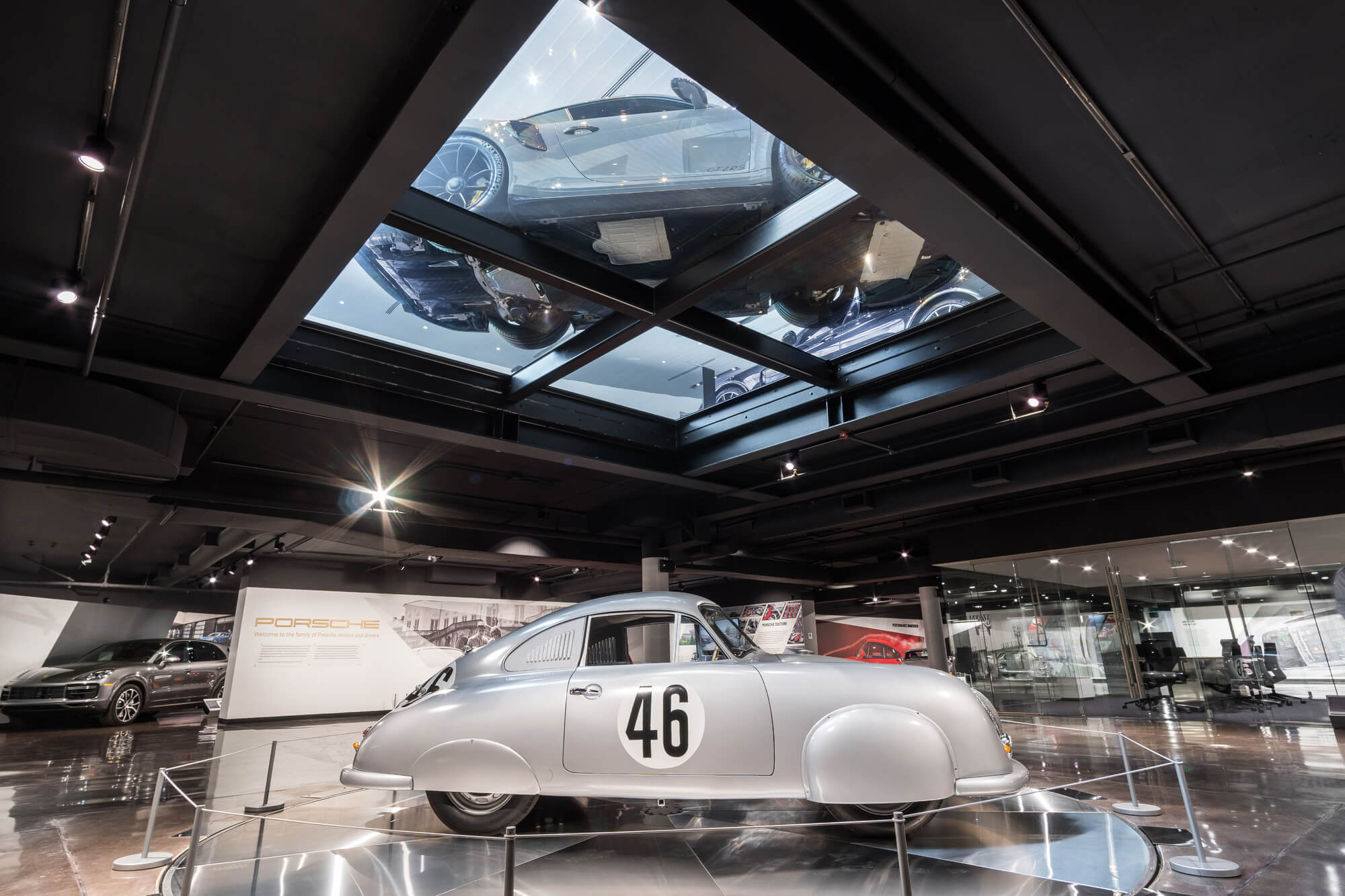 A vintage luxury car showroom in an industrial setting with glass floors and ceilings installed.