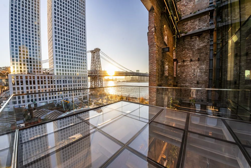 Rooftop glass observation deck with city skyline views and transparent flooring panels.
