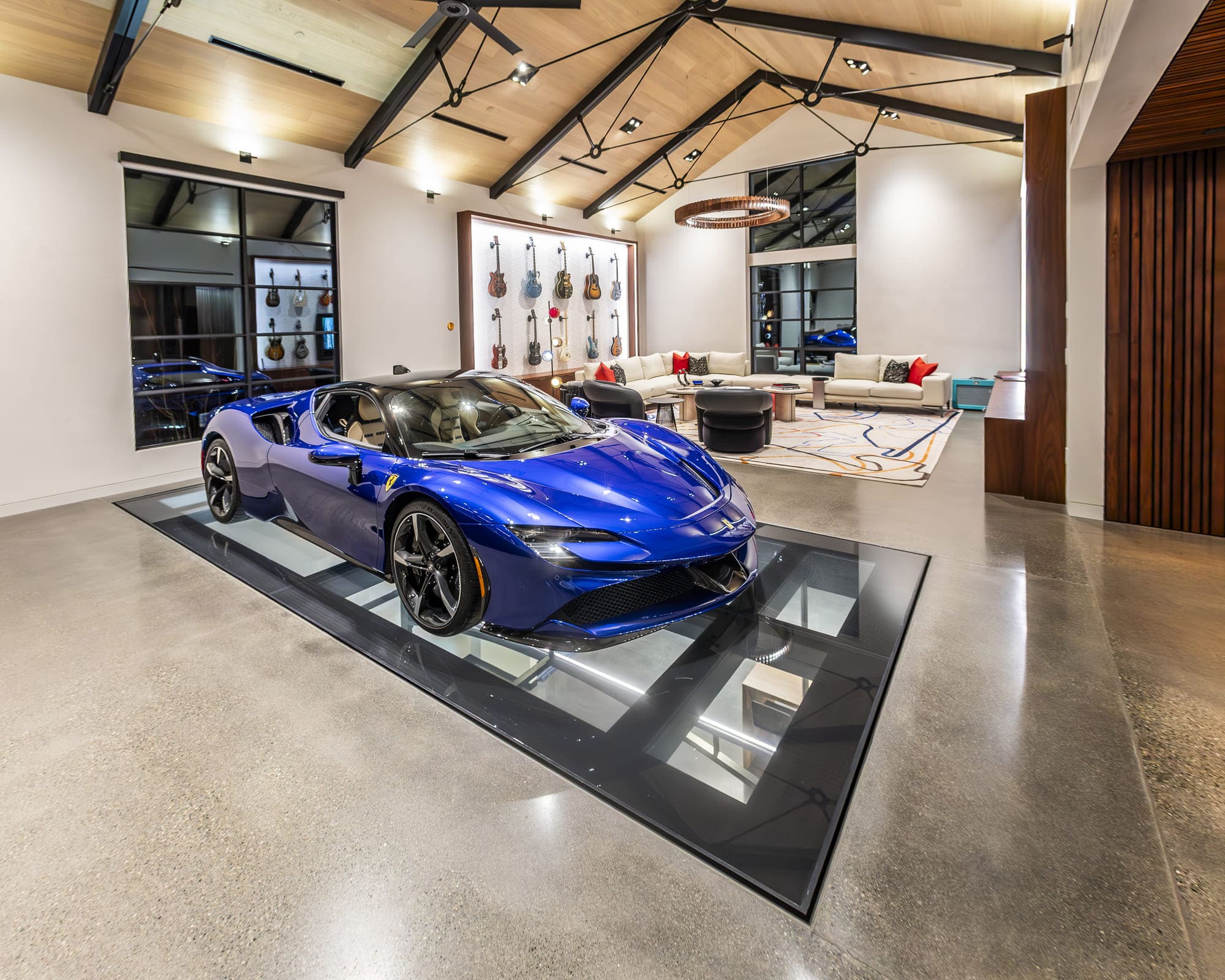A modern living room with displays of a guitar collection and a blue luxury car.