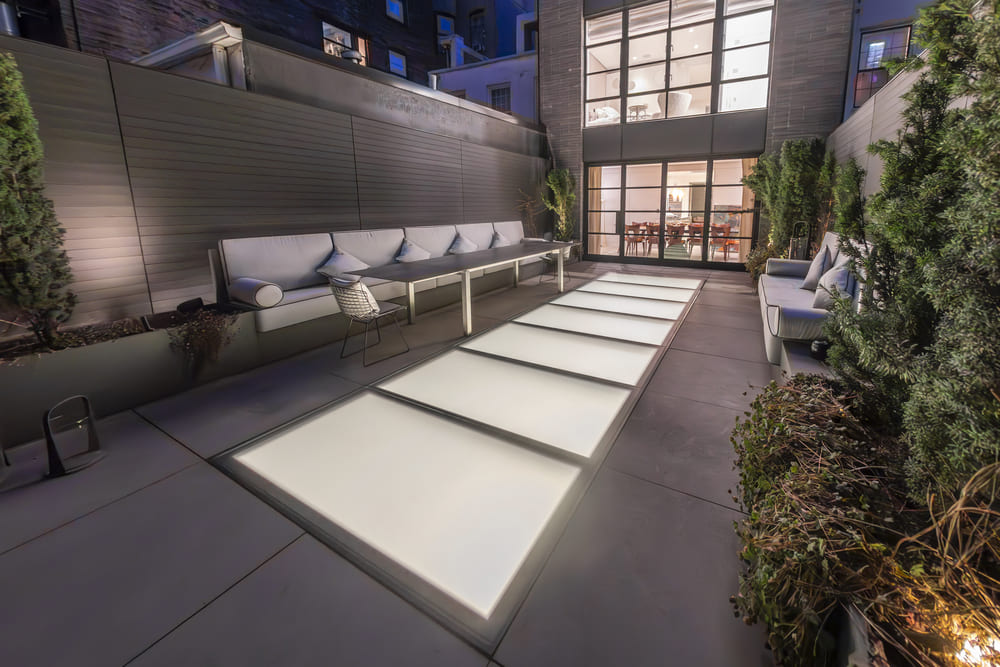 Rooftop terrace with large rectangular flat skylights illuminating the walkway.