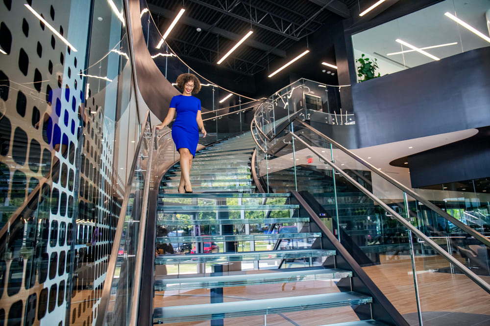 Person walking down a modern glass staircase with metal railings.