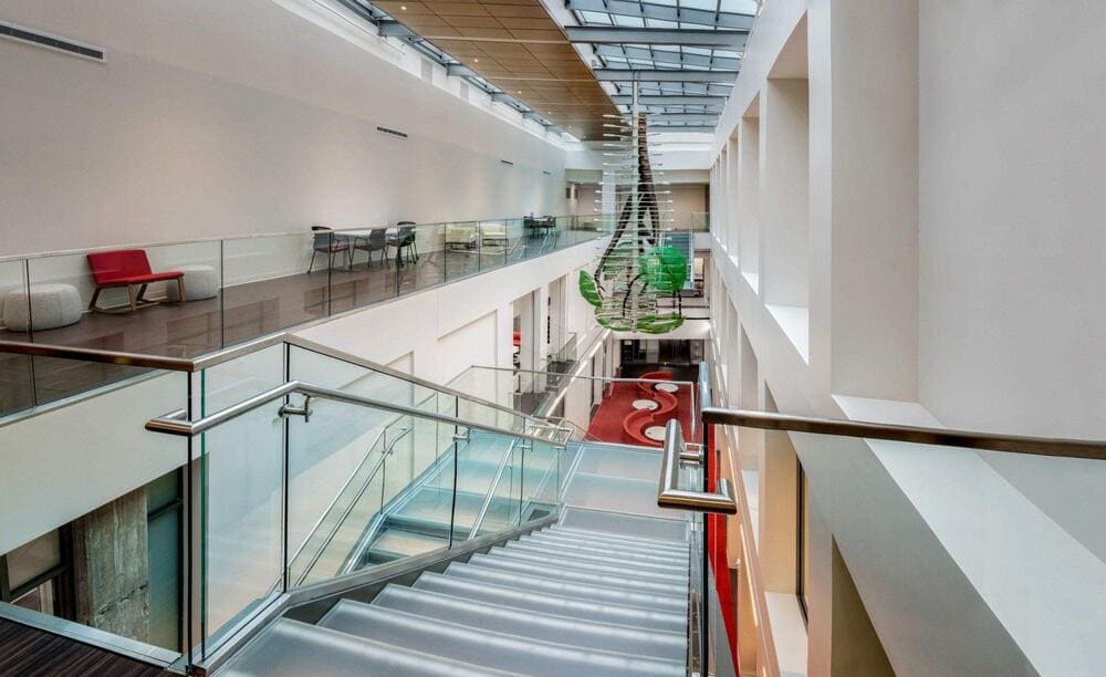 Floating staircase with glass railing along a bright hallway.