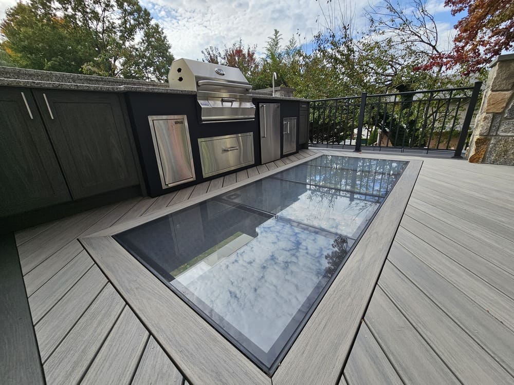 Contemporary deck design with a large glass floor panel offering a clear view of the space below.