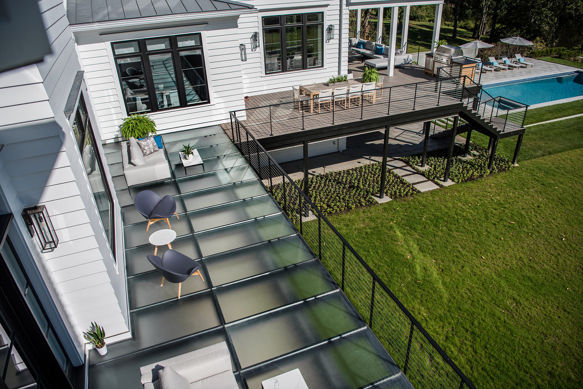 Backyard deck with clear glass flooring beside a swimming pool.