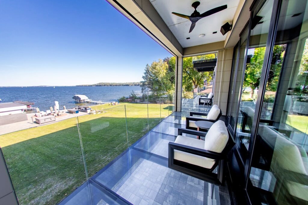 A glass veranda overlooking a wide backyard and the ocean.