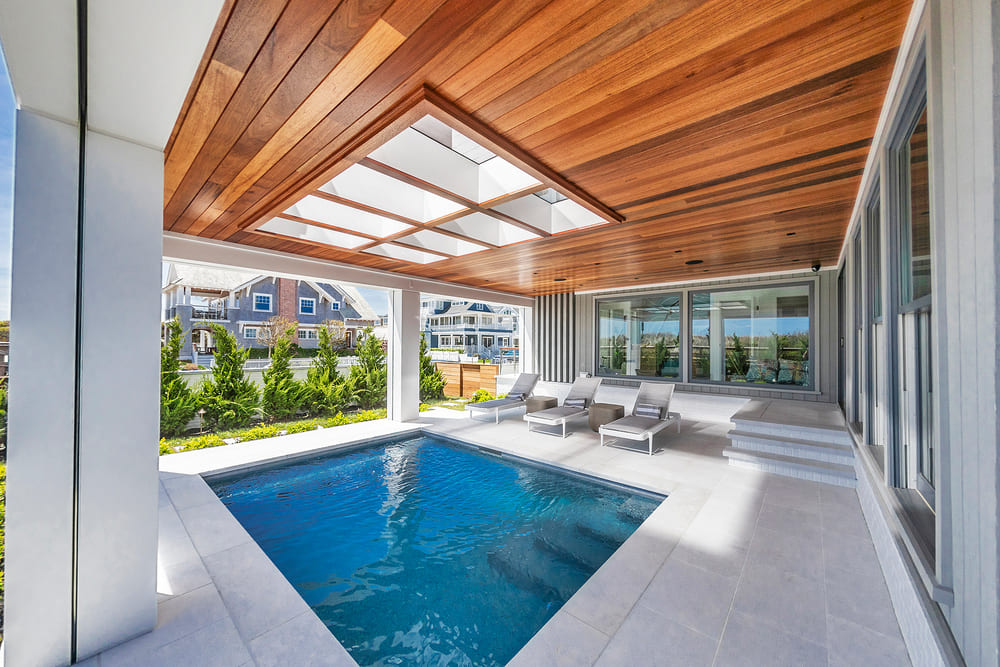 Luxury pool area with a wooden ceiling and glass panels enhancing the bright and open architectural design.