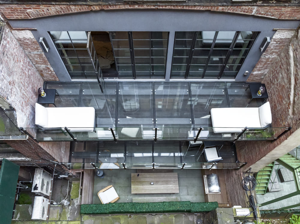 A suspended glass balcony attached to an industrial-style brick building.