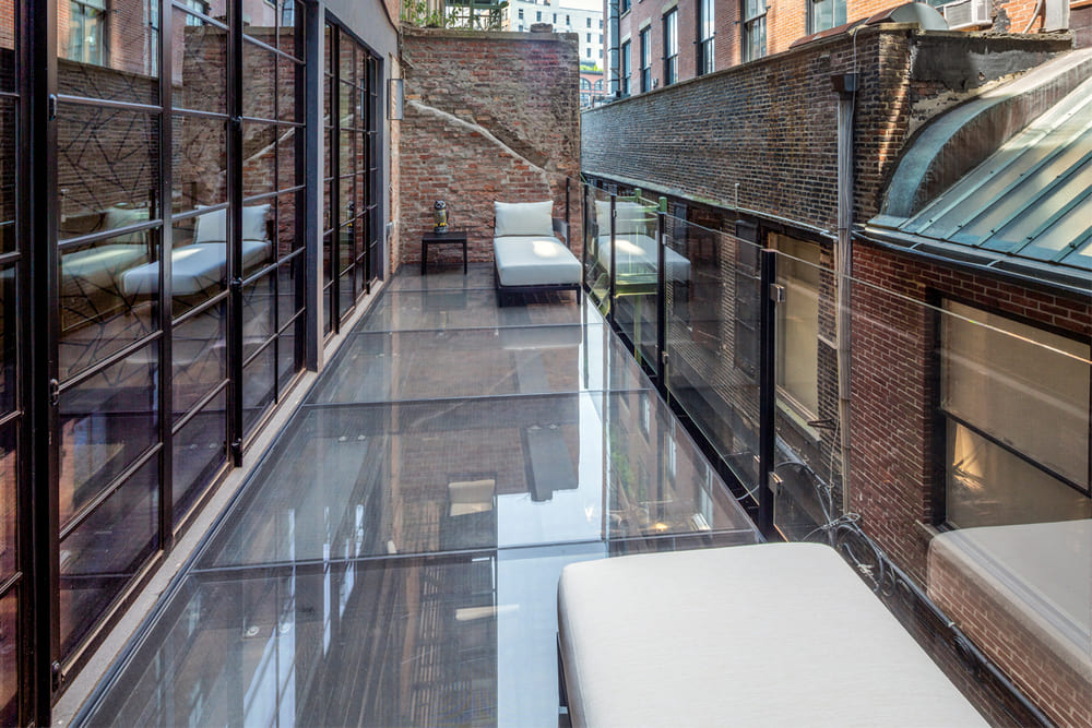 An outdoor glass patio on a street with brick houses and buildings.