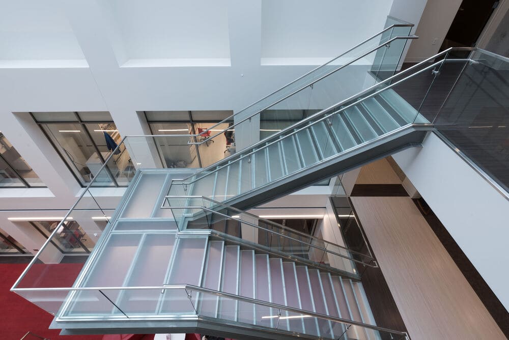 Multi-level glass staircase in a bright open atrium.