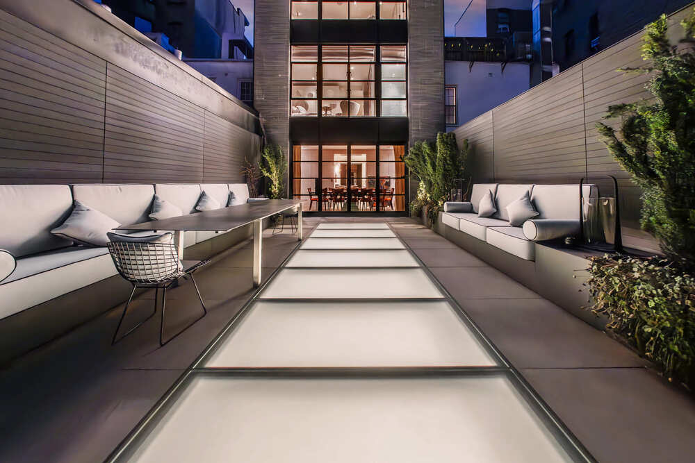 A patio with skylights on its aisle and modern outdoor living furnishings.