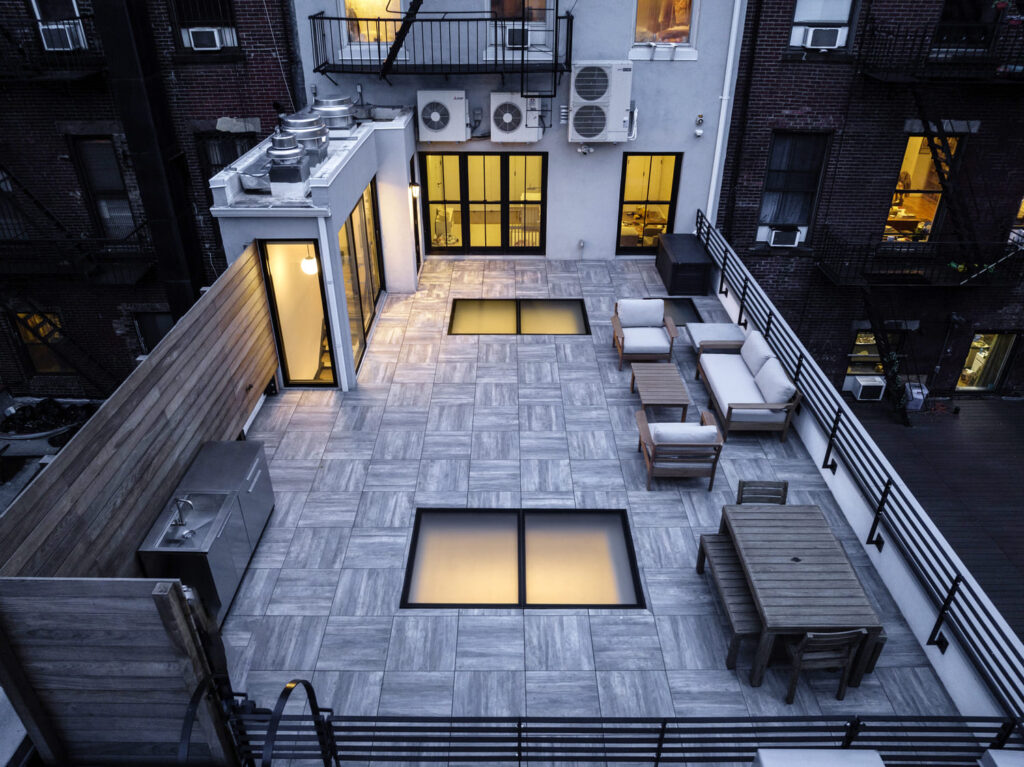 A wide-angle view of a rooftop with skyfloors, and outdoor sofas and tables.