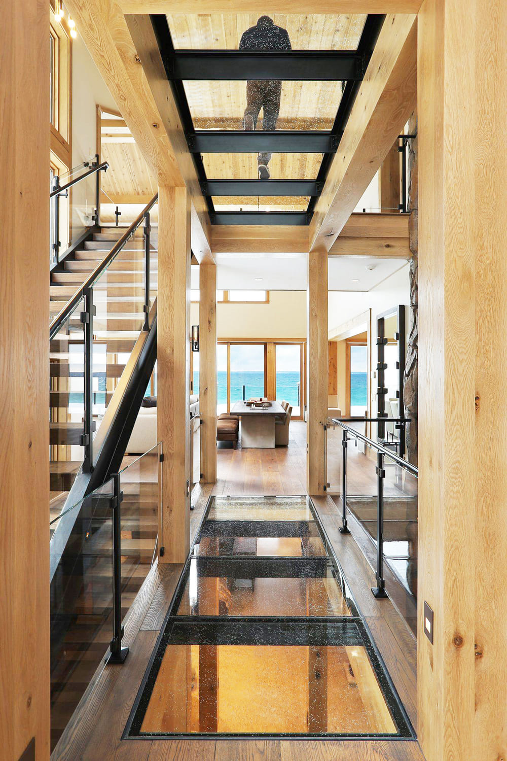 Wooden staircase next to a hallway with transparent glass floor walkway.