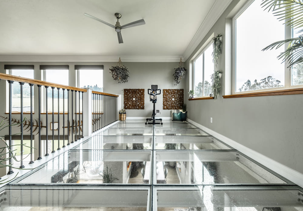Modern home interior with a clear glass walkway and glass panels over an open floor.