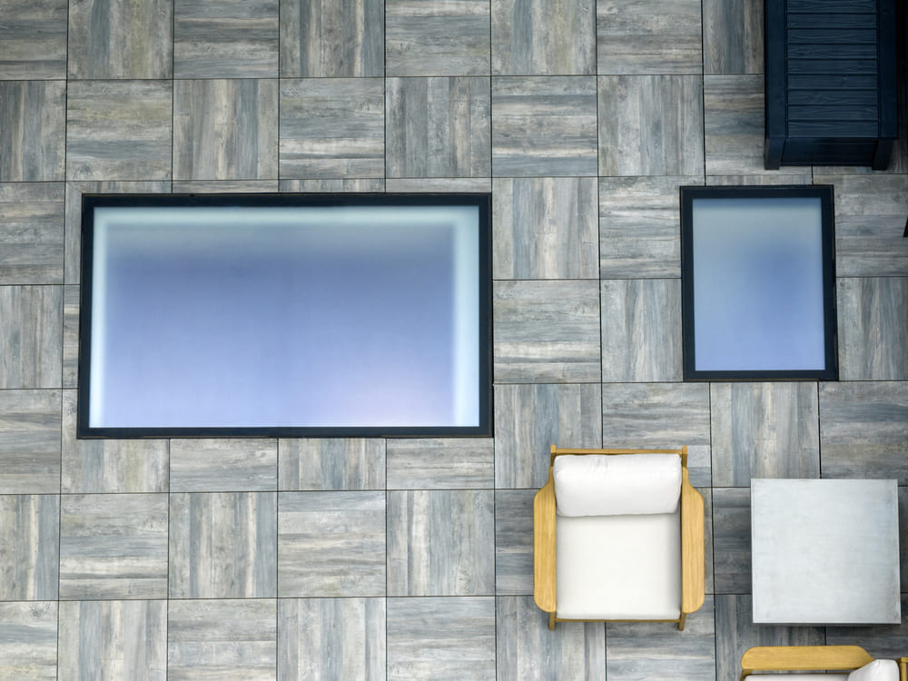 A modern terrace with square glass floor panels integrated into patterned stone tiles.