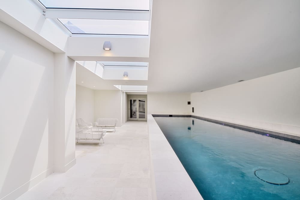 Indoor swimming pool area featuring a series of long skylights across the ceiling.