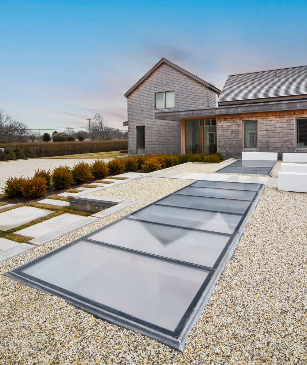 Contemporary house exterior with multiple large skylights installed on the roof.