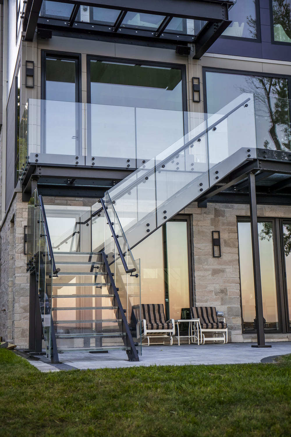 Exterior glass staircase attached to a contemporary house with large windows.