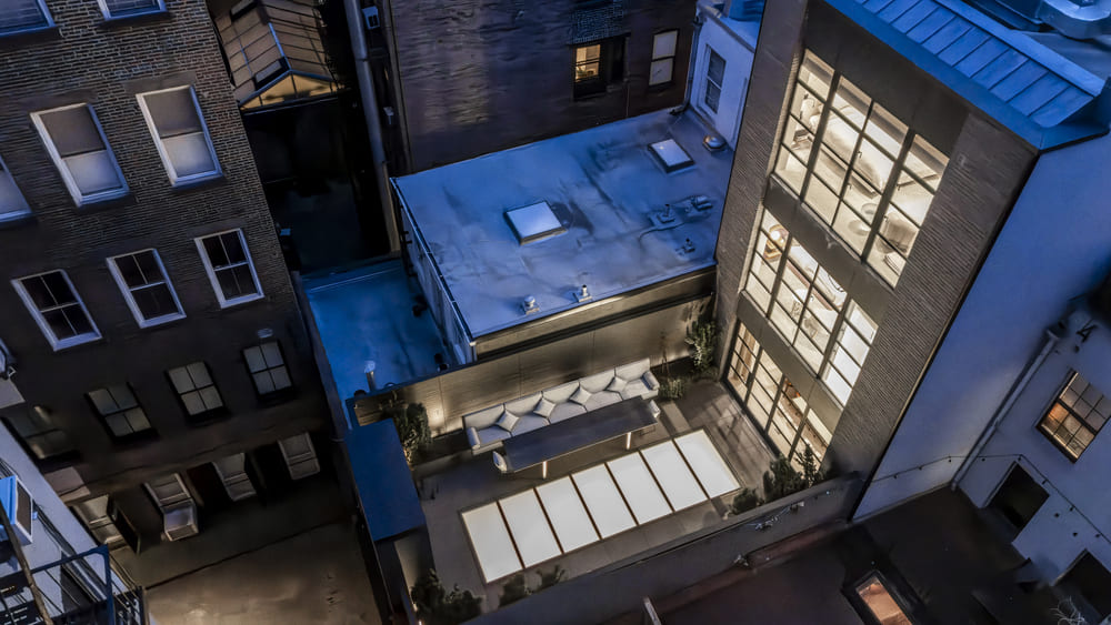 Urban rooftop with multiple glass skylights installed across adjoining buildings.