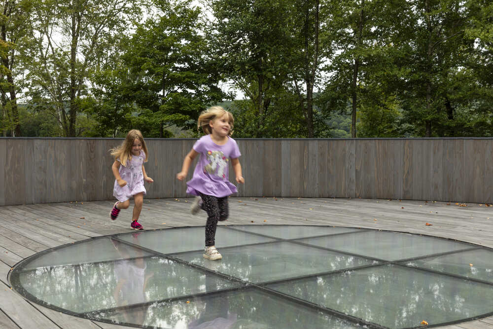 Two kids running above a glass floor panel.