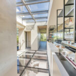 A walkable skylight located over the top of an interior glass floor flooding the modern luxury home with daylight.