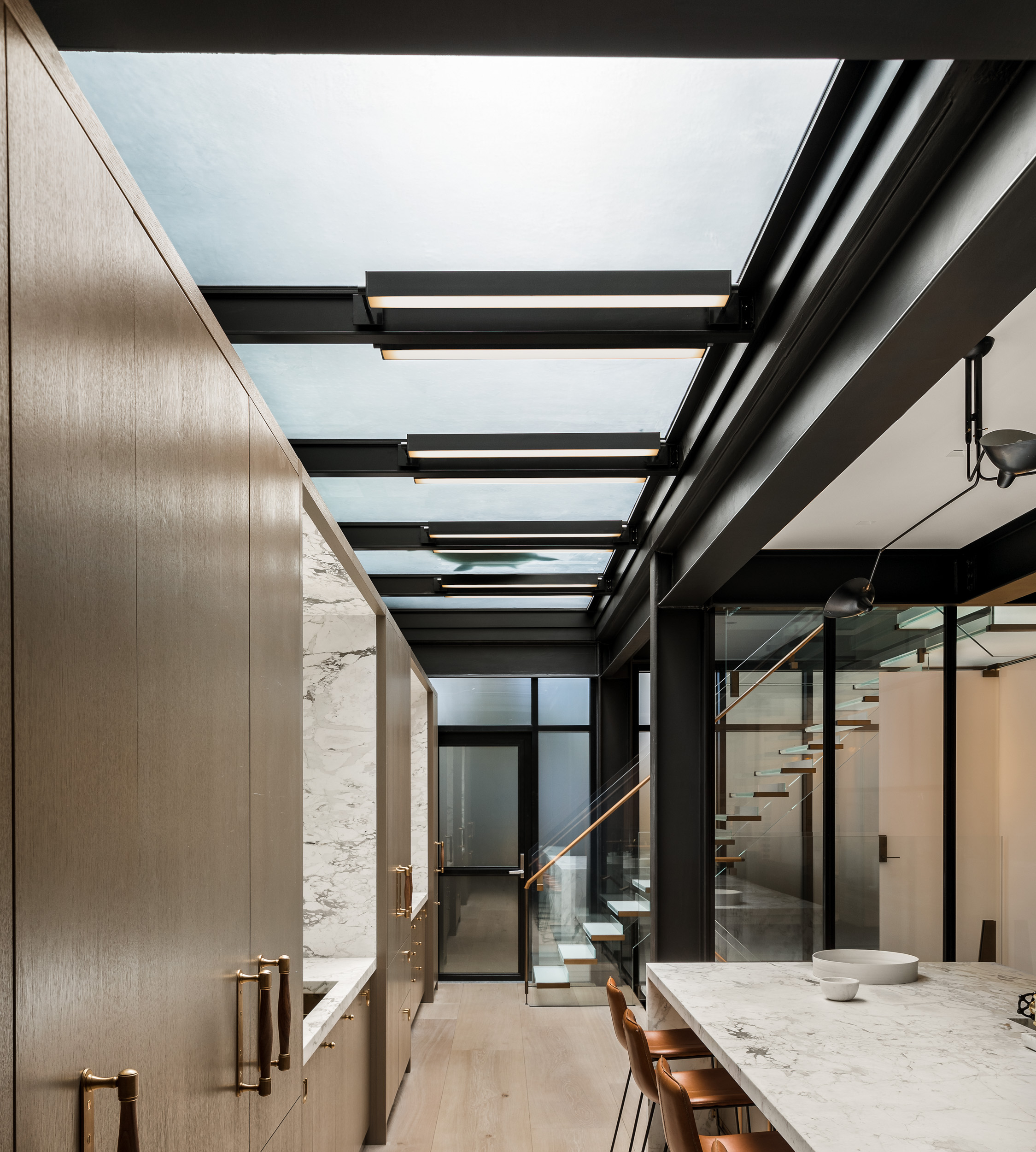 Kitchen area with overhead glass panels and black metal frames letting in natural light.